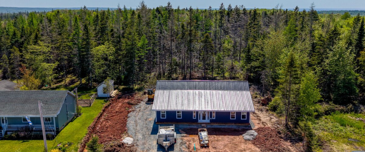 New navy home with a steel roof on a wooded lot in East Mountain, NS, seen from above