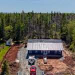 New navy home with a steel roof on a wooded lot in East Mountain, NS, seen from above