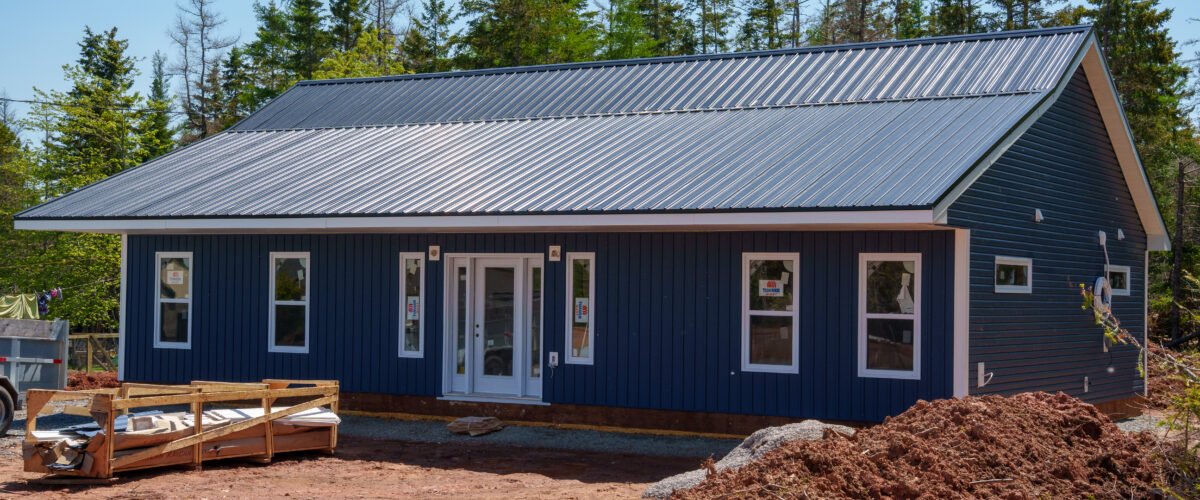 Front of a new single-storey home with navy siding and a steel roof in East Mountain, Nova Scotia