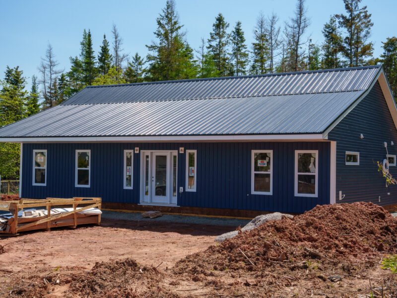 Front of a new single-storey home with navy siding and a steel roof in East Mountain, Nova Scotia