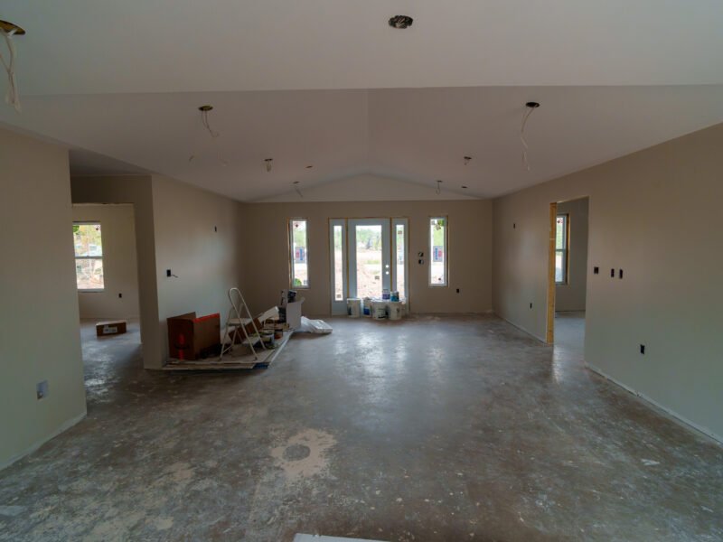 Open-concept living area under a vaulted ceiling at the drywall stage in a new East Mountain home