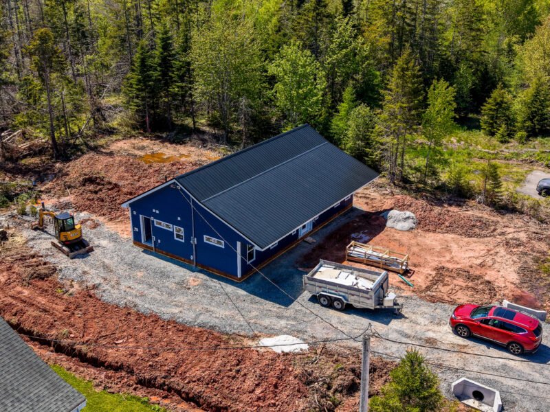Aerial side view of a navy house with a steel roof and site work in East Mountain, NS